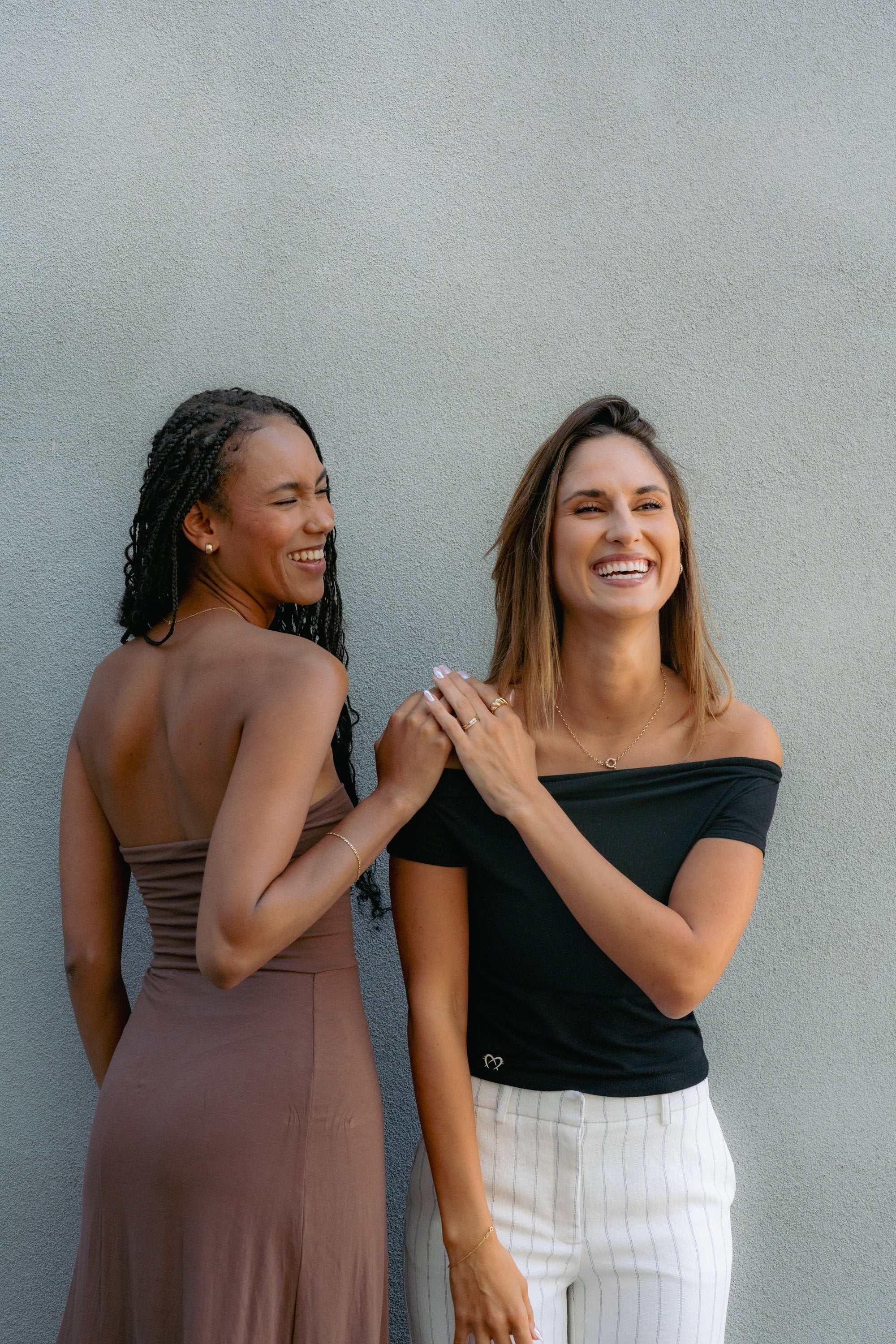 Two women smiling and standing side by side, exuding joy and friendship.