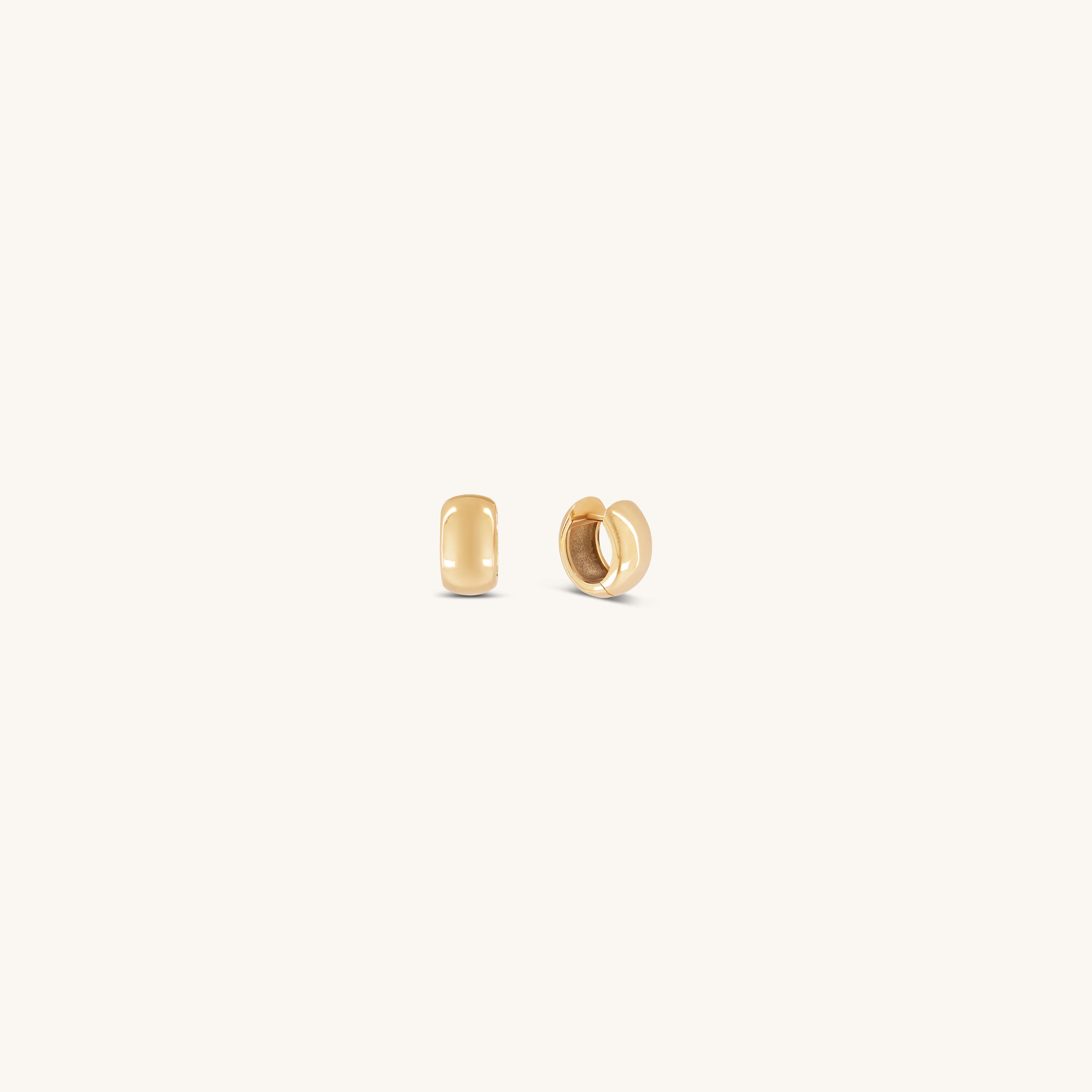 Two small, smooth Gabriel Huggies from Glasâje are displayed on a light beige background—one shown from the front and one from the side—offering an effortless, timeless staple for any jewelry collection.