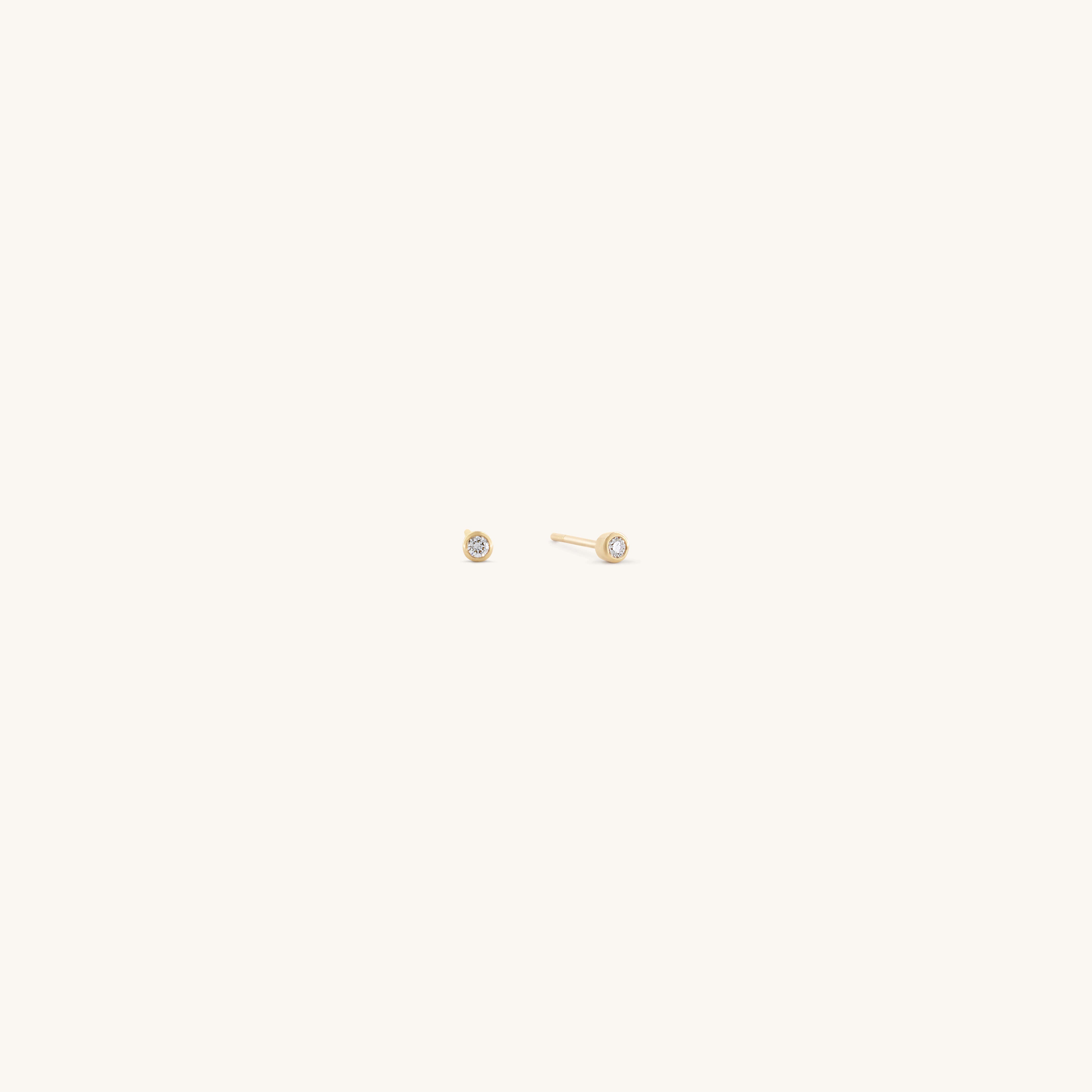 The Glasâje Satellite Studs feature small, round solid gold settings with a central clear gemstone, elegantly showcased against a plain light background.