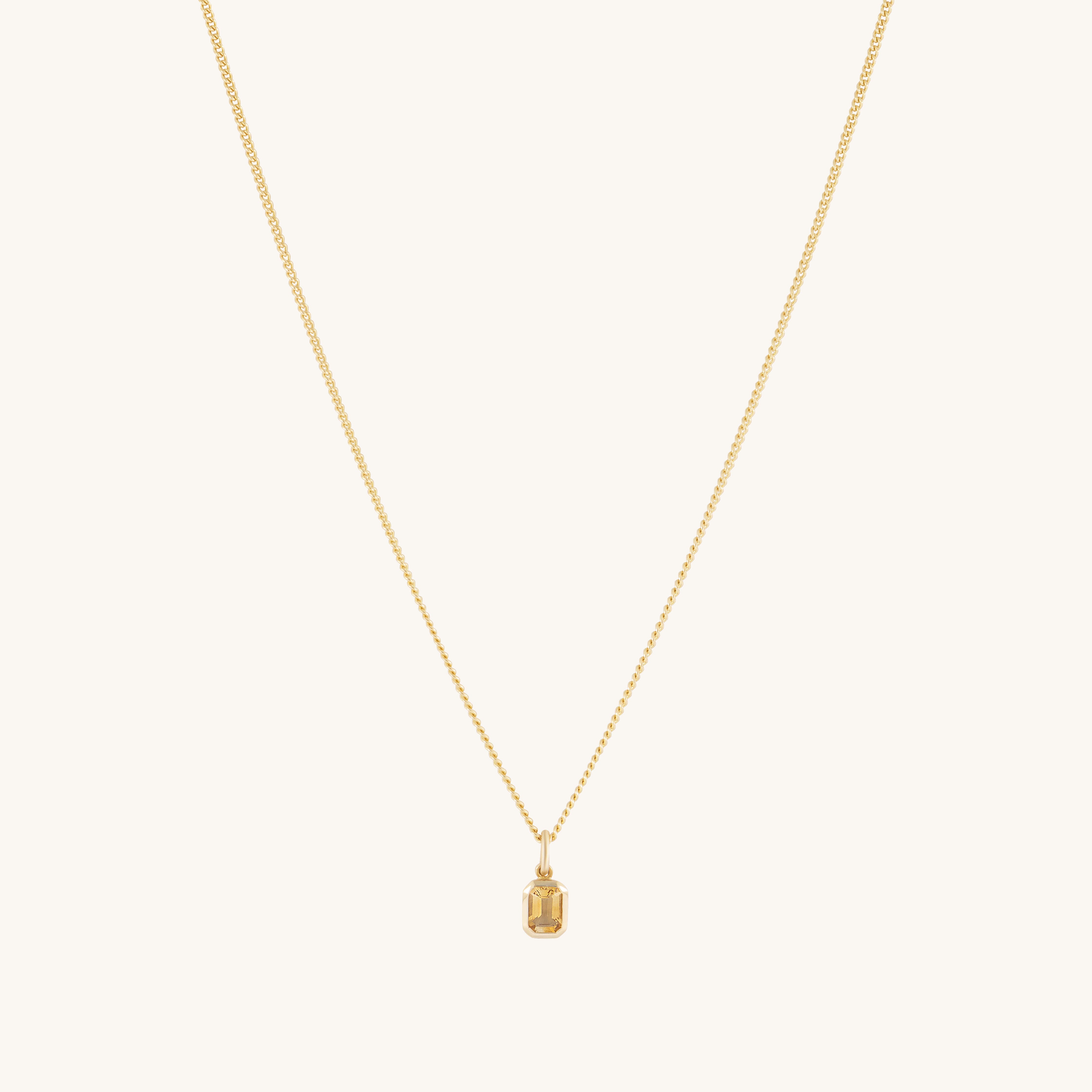 A fine gold chain necklace featuring a small rectangular pendant with an emerald-cut auburn citrine. Understated and elegant, the pendant stands out subtly against a simple backdrop.