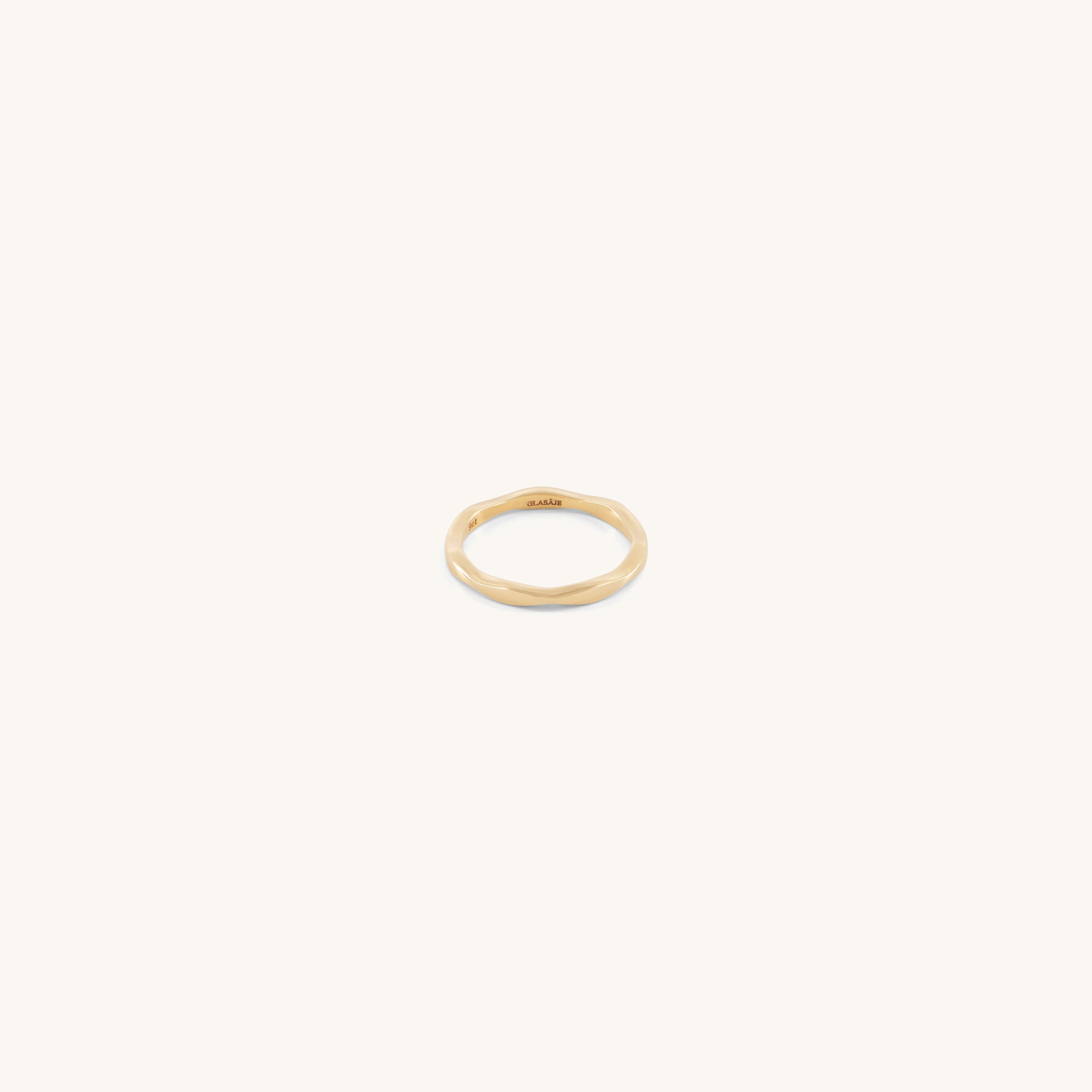 The Glasâje Ripple Stacking Ring is a slender 9ct solid gold band featuring an organic, wavy ripple design, shown against a plain, light background.
