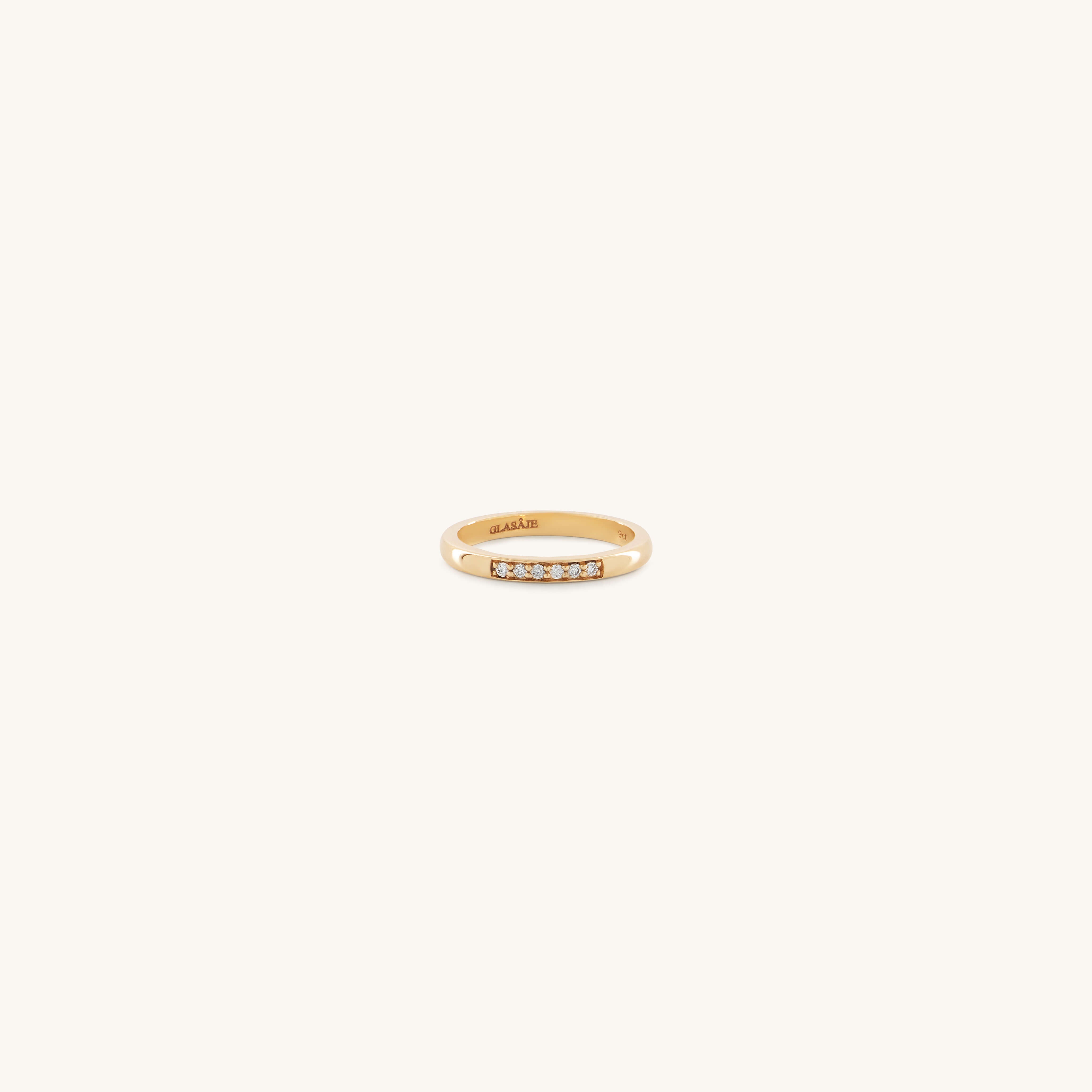 A gold ring with a minimalist design features a row of six small, sparkling diamonds. The setting is simple yet elegant, conveying a timeless charm.
