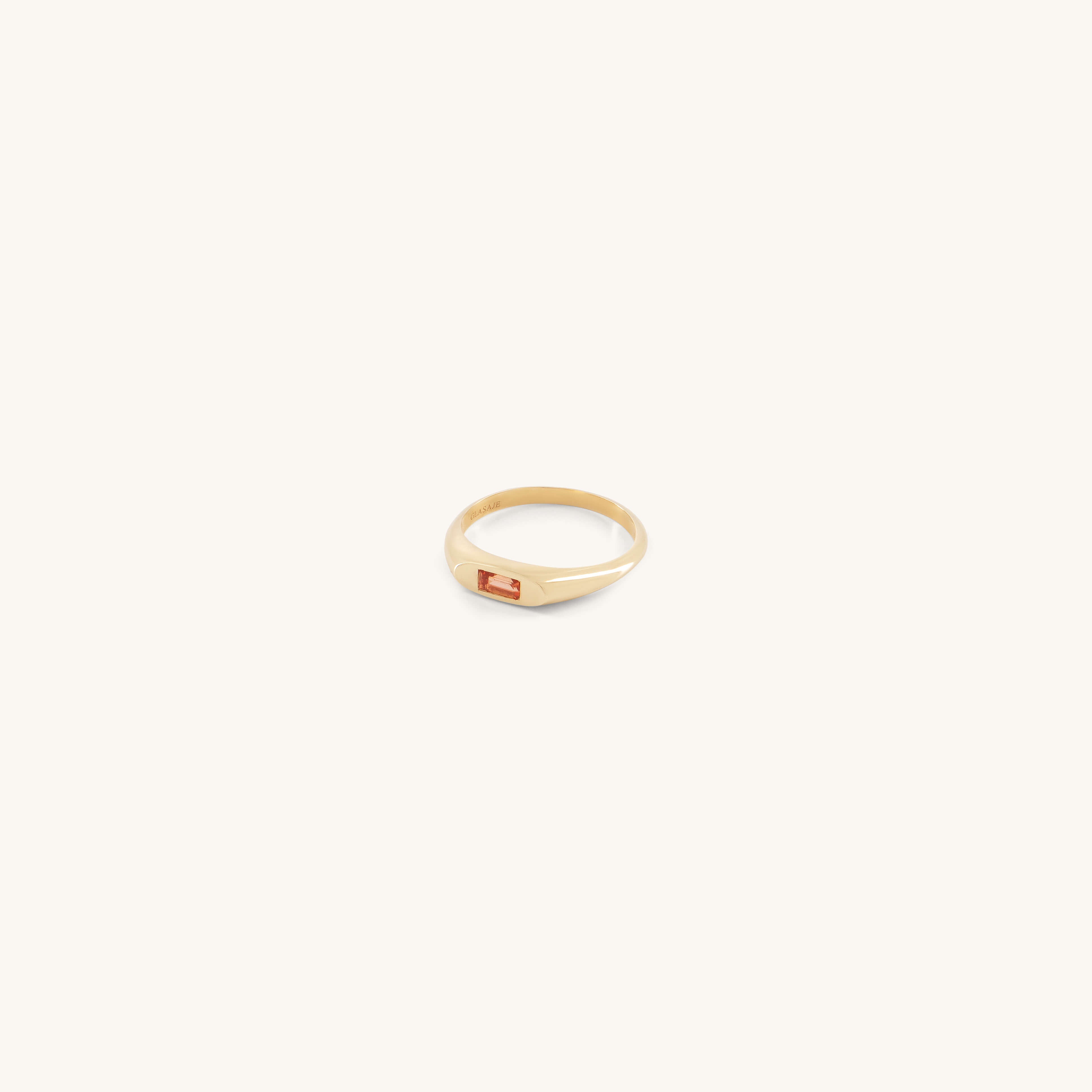 The Glasâje Tawny Ring, with its solid gold signet band and rectangular auburn citrine stone, is displayed on a plain, light background.