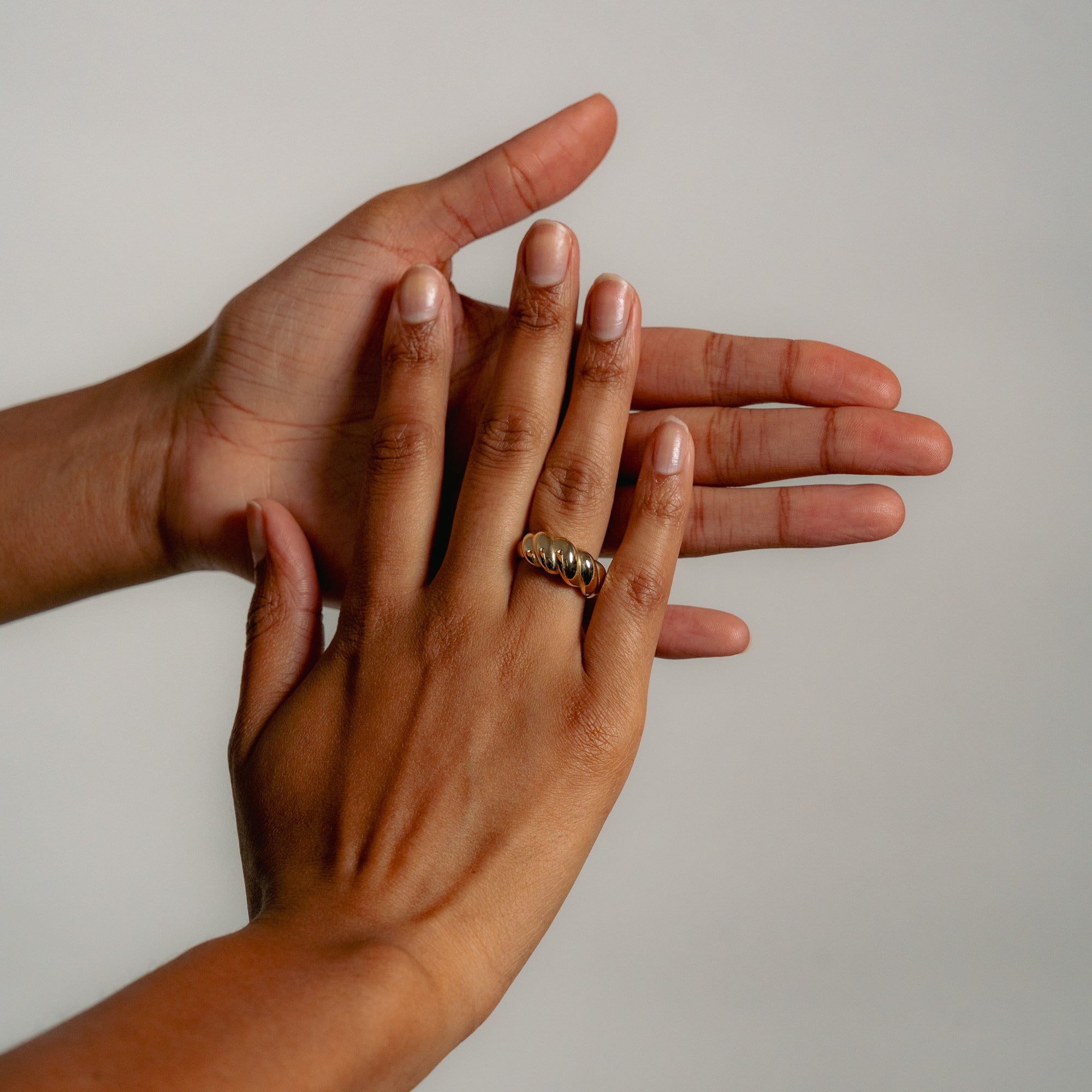 Two hands with natural nails rest against a neutral background. The top hand wears the Glasâje Lune Ring in 9ct solid gold on the middle finger, elegantly displayed above the other open hand.